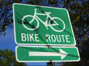 Green bike route sign with arrow.