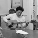 Delta Bohemian Gene Joe playing Magical Madge's Epiphone shortly after he restrung it. Note the Marshall Bouldin pencil sketch behind him. Photo by The DB