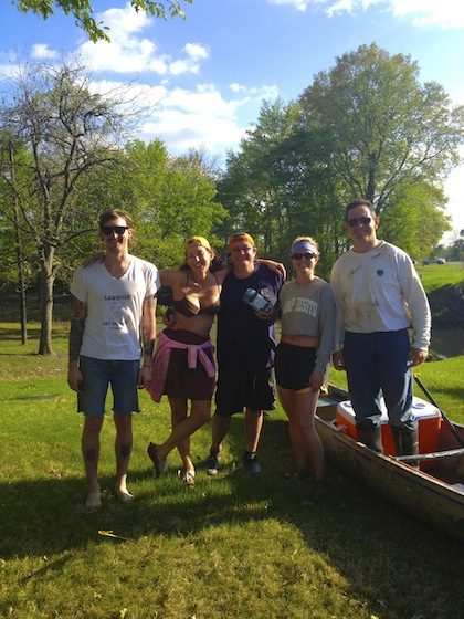 Five friends posing by a canoe.