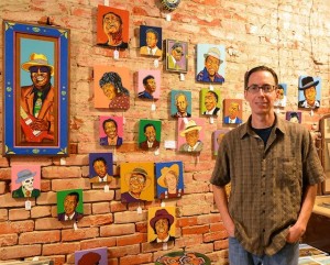 Man in front of wall art of musicians.