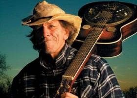 Man in a hat holding a guitar.