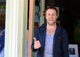 Smiling man in blue jacket giving thumbs up.