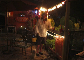 Man with dog at outdoor bar with lights.