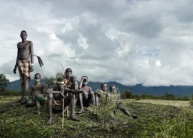 Group of men in a field with a rifle.