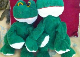 Two green plush frog toys hugging.