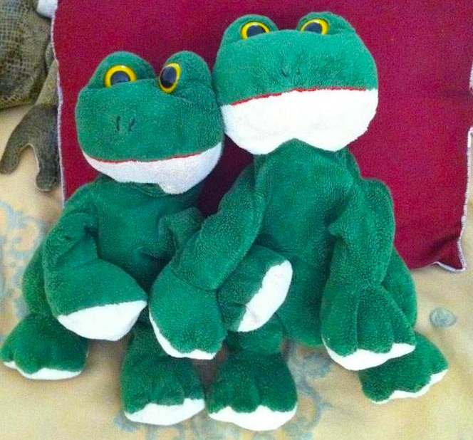 Two green plush frog toys hugging.