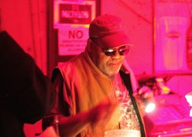 Man with beard wearing sunglasses in red light.