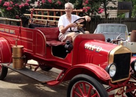 A red vintage fire truck with a driver.