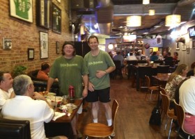 Men at a bar with wooden chairs.