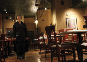 A woman stands in a dimly lit restaurant.