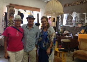 Three people stand in a shop with vintage decor.