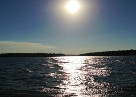 Sun reflecting on calm lake water.