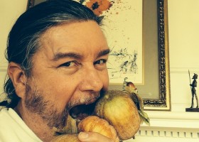 Man eating fruit with painting in background.