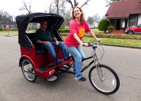 Woman riding a red bicycle rickshaw.