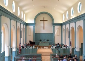 A church interior with a cross above the altar.