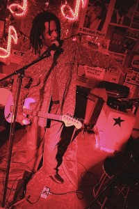 Man playing guitar on stage with microphone.