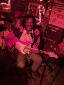 Man plays pink electric guitar on stage.