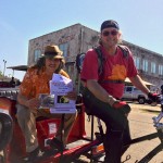 Two men in a rickshaw holding a CD release flyer.