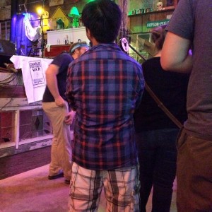 Man in plaid shirt standing with others.