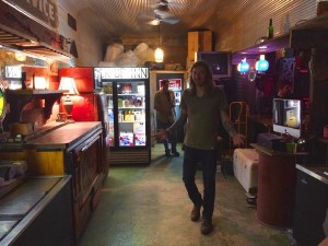 Man in bar with a drink menu and customers.