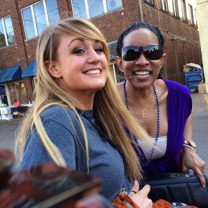 Two women smiling, one with sunglasses.