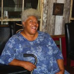 Smiling woman in blue shirt holding a cane.