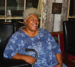 Smiling woman in blue shirt holding a cane.