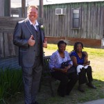 Man in grey suit with two women on bench.