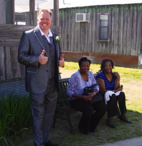 Man in grey suit with two women on bench.