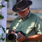 Man in hat taking photo with camera.