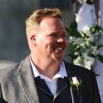 Smiling groom in a suit and boutonniere.