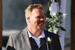 Smiling groom in a suit and boutonniere.