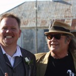 Two men smiling, one wearing a suit.