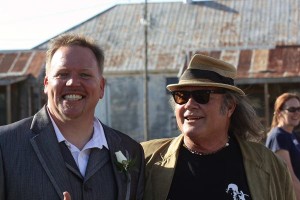 Two men smiling, one wearing a suit.