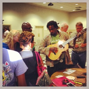 Man playing guitar with friends in a room.