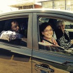 Three people in a car, smiling.