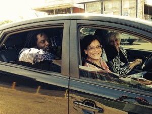 Three people in a car, smiling.