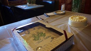 A wedding cake on a table with a gift box.