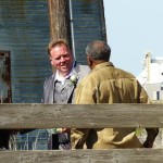 Three men standing in front of a wooden building.