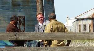 Three men standing in front of a wooden building.