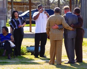 Group of people standing, some smiling, outdoors.