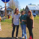 Three friends stand in front of an American sign.