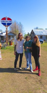 Three friends stand in front of an American sign.