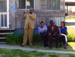 Four people posing outside a wooden house.