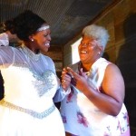 Two women, one in a white dress, smiling.