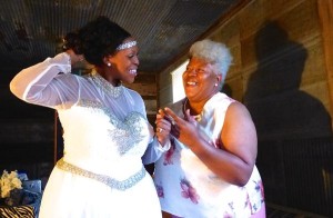 Two women, one in a white dress, smiling.