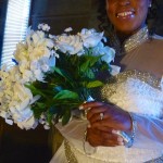 Bride holding white bouquet in wedding dress.