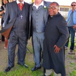 Three men in suits stand outdoors.