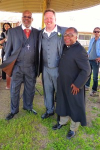 Three men in suits stand outdoors.