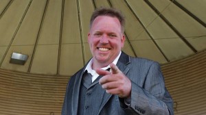 Man in suit smiling with finger pointing.